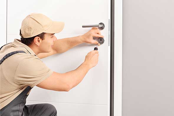 ALS Young locksmith installing a lock on a door